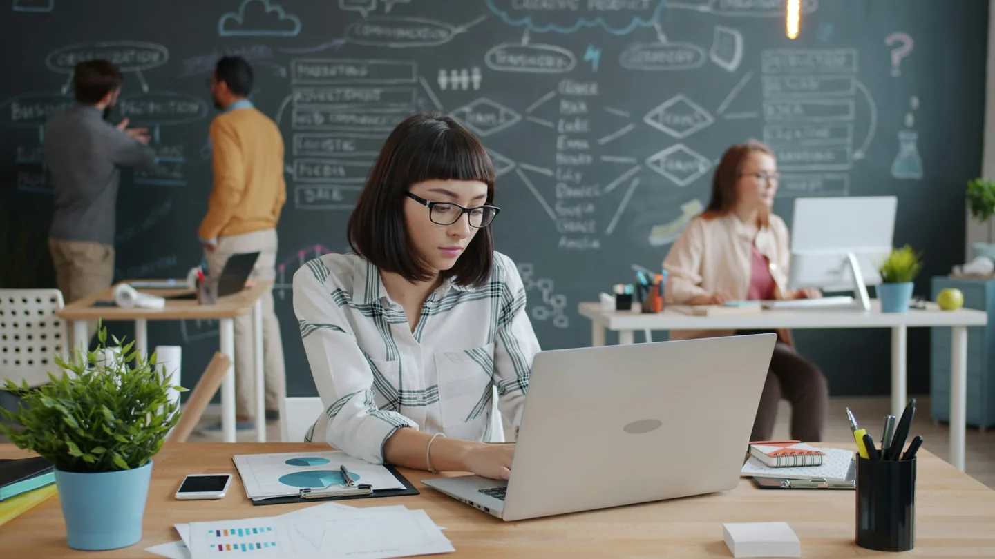 Mitarbeiterin arbeitet konzentriert an einem Laptop in einem modernen Büro