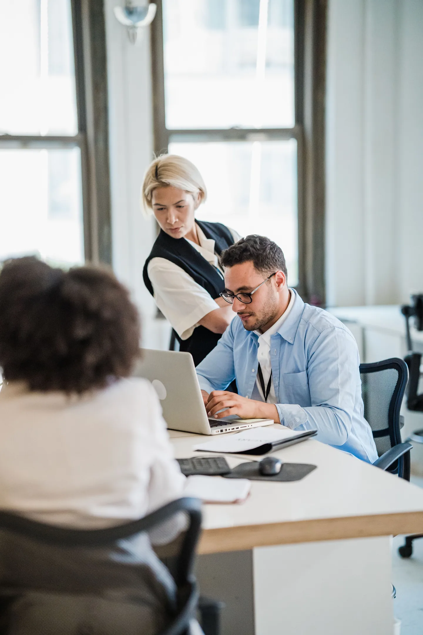 Ein Team arbeitet gemeinsam an einem Laptop in einem hellen Büro